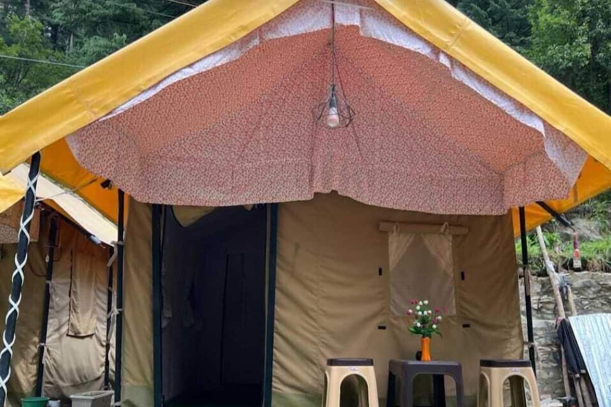 A tent with a partially open entrance, a small table with a vase, and two stools outside.