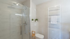 A modern bathroom with a glass-enclosed shower, a toilet, and a towel rack. - 2-room apartment with parking in luxury residence in Alpe d'Huez (Huez)