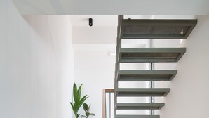 Eine moderne Treppe mit weißen Stufen und einem Metallgeländer, das zu einer Plattform mit einem Blumentopf führt.