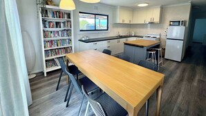 Een moderne keuken met een houten tafel, twee hanglampen, een inbouwboekenkast en uitzicht door een raam.