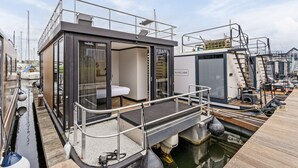 Eine moderne, schwimmende Konstruktion mit einem gläsernen Raum, einer Terrasse und einem Wasserkanal.
