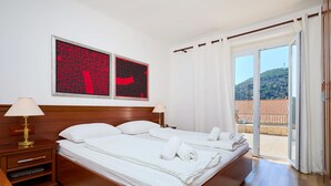 Una camera d'albergo con un letto grande, due comodini e vista su un edificio con tegole rosse attraverso la porta vetrata.