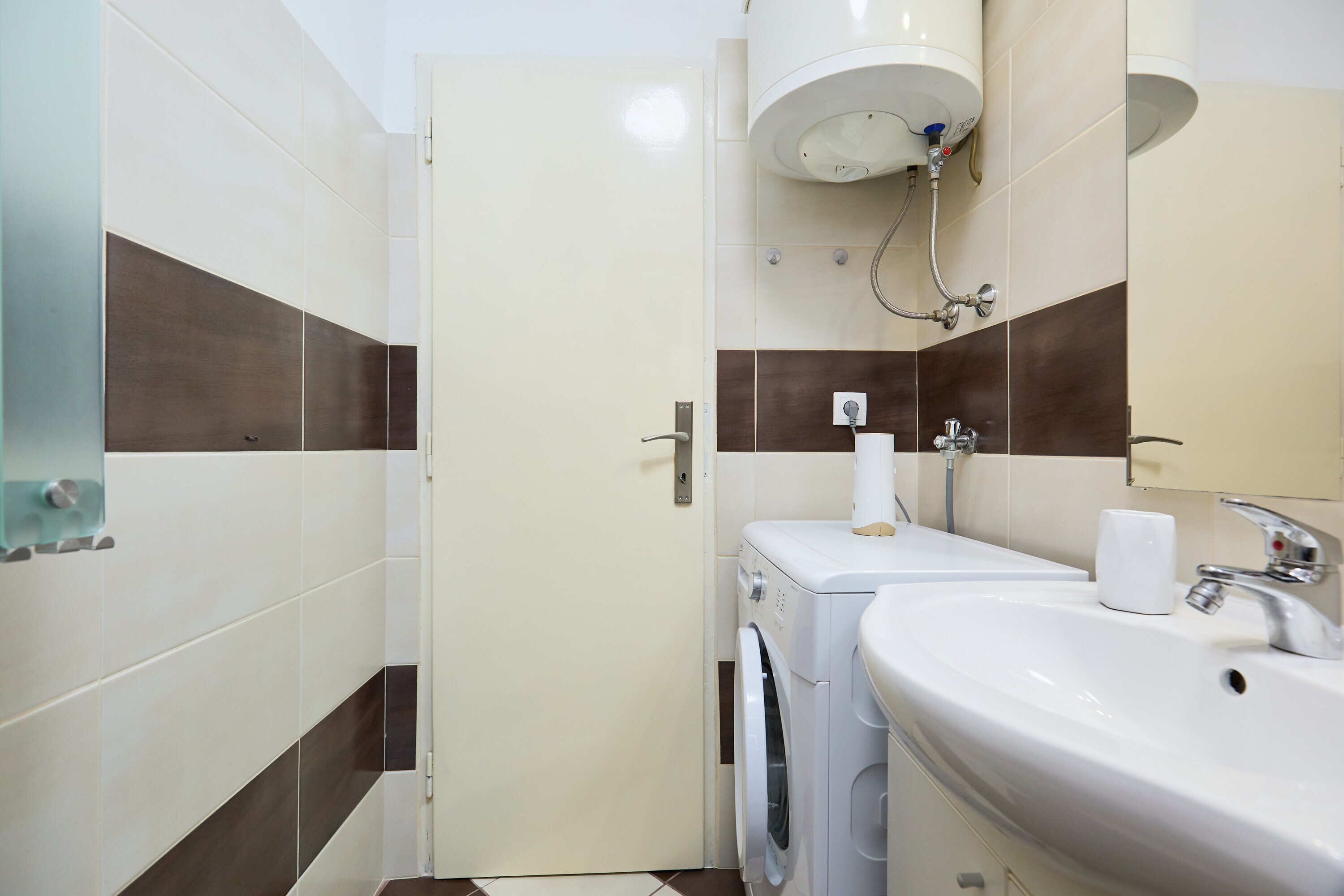 A compact bathroom with a washing machine, a sink, and a toilet.