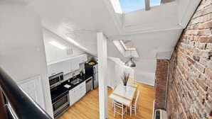 Kompakti keittiö, jossa on valkoiset kaapit, musta työtaso ja kattovalokuvio.