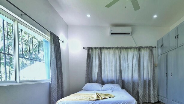 A bedroom with a bed, curtains, an air conditioning unit, and a wardrobe. - Cozy 1-bed Apt in Whim Estate-near Scarborough (Scarborough)