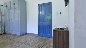 A room with a large grey wardrobe, a blue door, and a small wooden table with a remote control and papers. - Cozy 1-bed Apt in Whim Estate-near Scarborough (Scarborough)