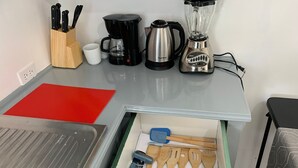 A kitchen counter with a coffee maker, a blender, and a drawer with wooden utensils. - 1 Bed Studio Apt - Parking, Wifi, Mountain Views (Scarborough)