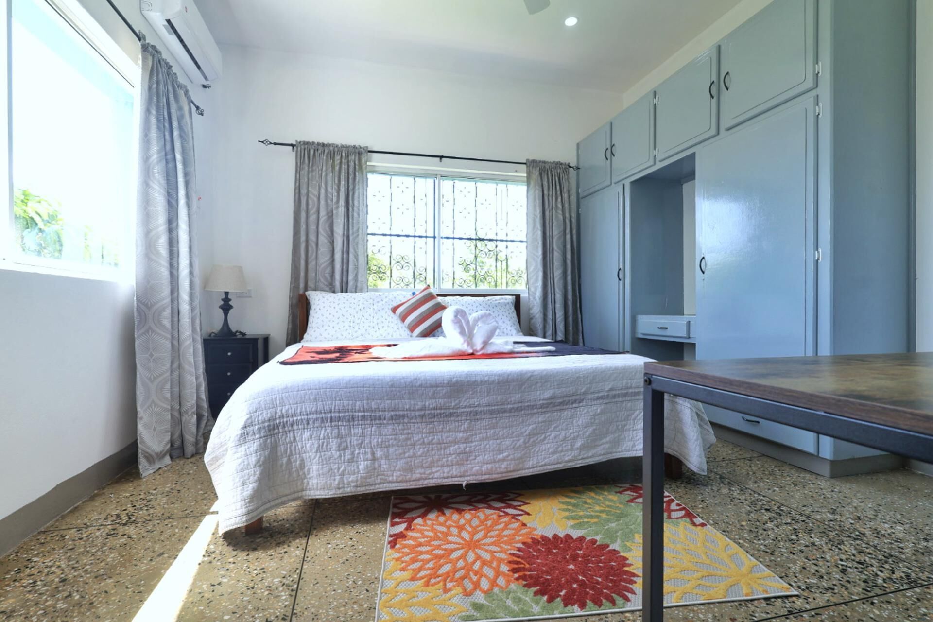 A bedroom with a bed, curtains, a window, a desk, and a wardrobe.