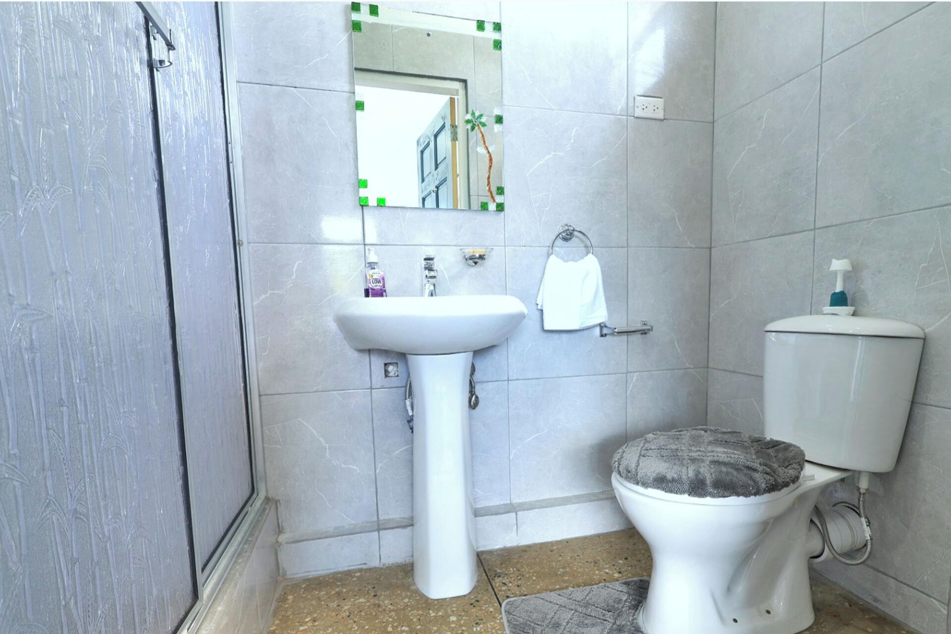 Une salle de bain avec un lavabo blanc, des toilettes et un miroir.