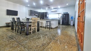Uma cozinha moderna com bancadas de granito, uma área de refeições com mesa redonda e cadeiras, e uma ilha integrada com banquetas.