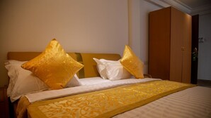 Quarto de hotel com cama, duas almofadas, mesa de cabeceira e guarda-roupa.