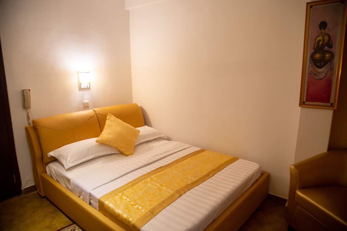 Une chambre d’hôtel avec un lit, une chaise, un tableau au mur et un téléphone fixé au mur.