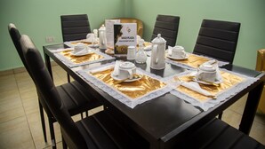 Mesa de jantar posta para seis lugares, com jogo americano, louça branca e um letreiro com o cardápio.