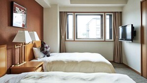A hotel room with two beds, a TV, a lamp, and a window with curtains.