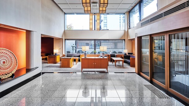 A spacious lobby with a central seating area, large windows, and a modern design.
