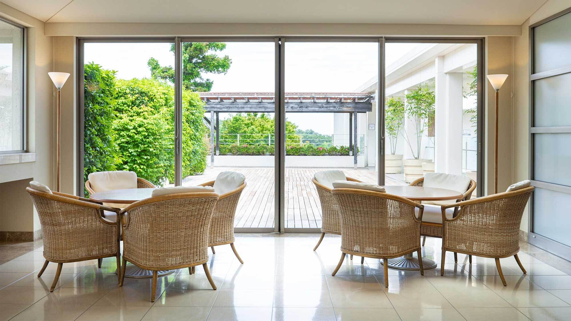 A spacious indoor area with wicker furniture and a large sliding glass door leading to an outdoor patio.