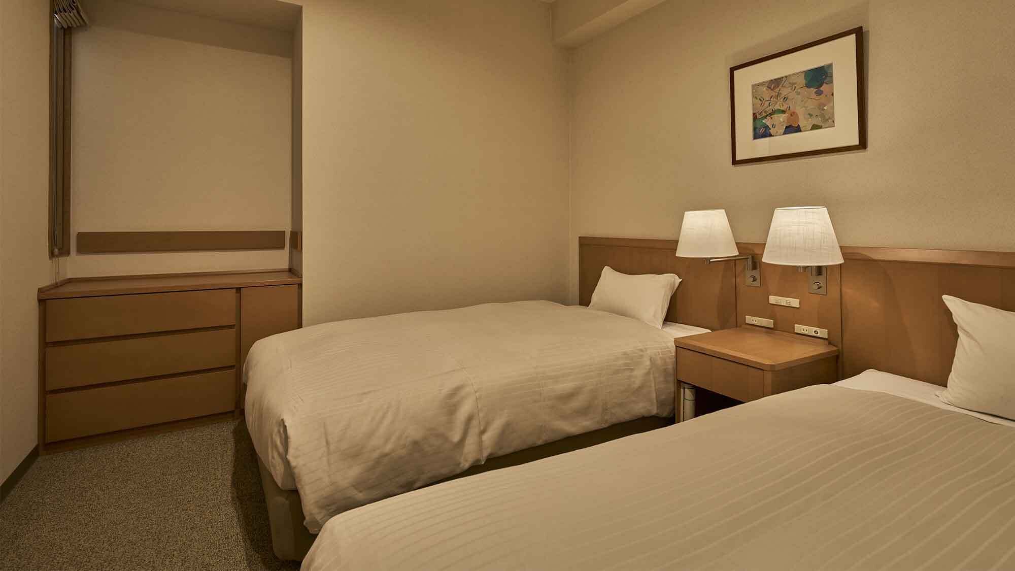 A hotel room with two beds, a dresser, and a nightstand with lamps.