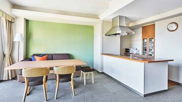 A modern hotel room with a dining area, a kitchenette, and a green accent wall.