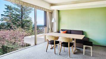 Una habitación moderna con un ventanal grande, una mesa de comedor, dos sillas, un sofá y una lámpara.
