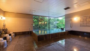 A modern bathroom with a glass-enclosed hot tub, a shower area, and a view of lush greenery outside. - Tokyu Vacations Izukogen (Ito)