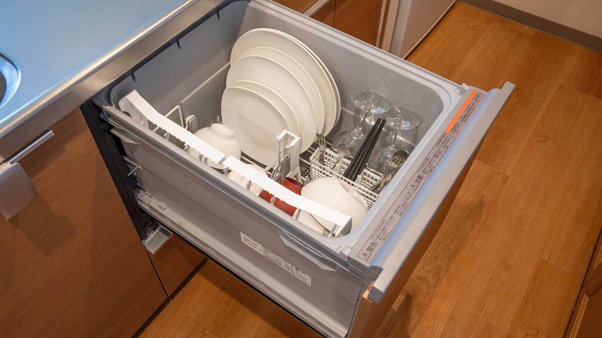 A kitchen drawer with white plates, bowls, and utensils.