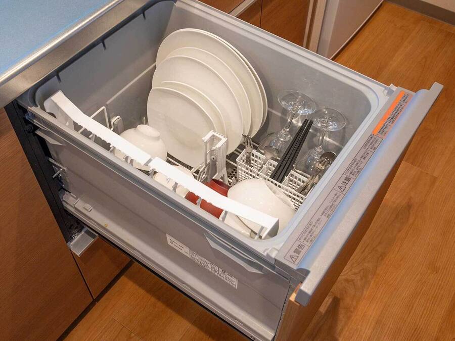 Eine Küchenschublade mit weißen Tellern, Schüsseln und Besteck.