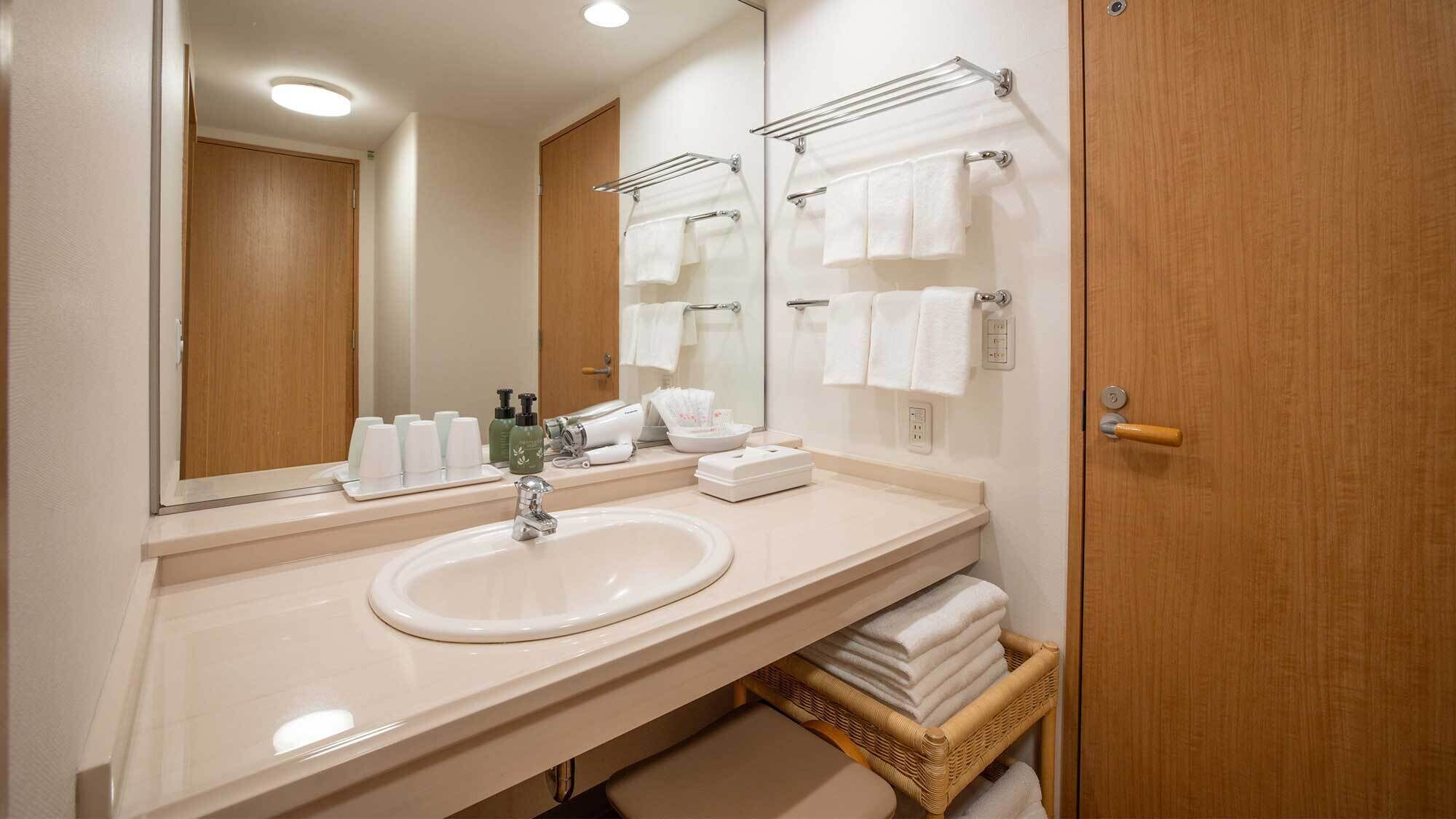 A hotel bathroom with a large mirror, a sink, and a towel rack.