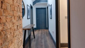 A narrow hallway with a sloped ceiling, a wooden table, and a door at the end. - Harrisons Aparthotel (Liverpool)