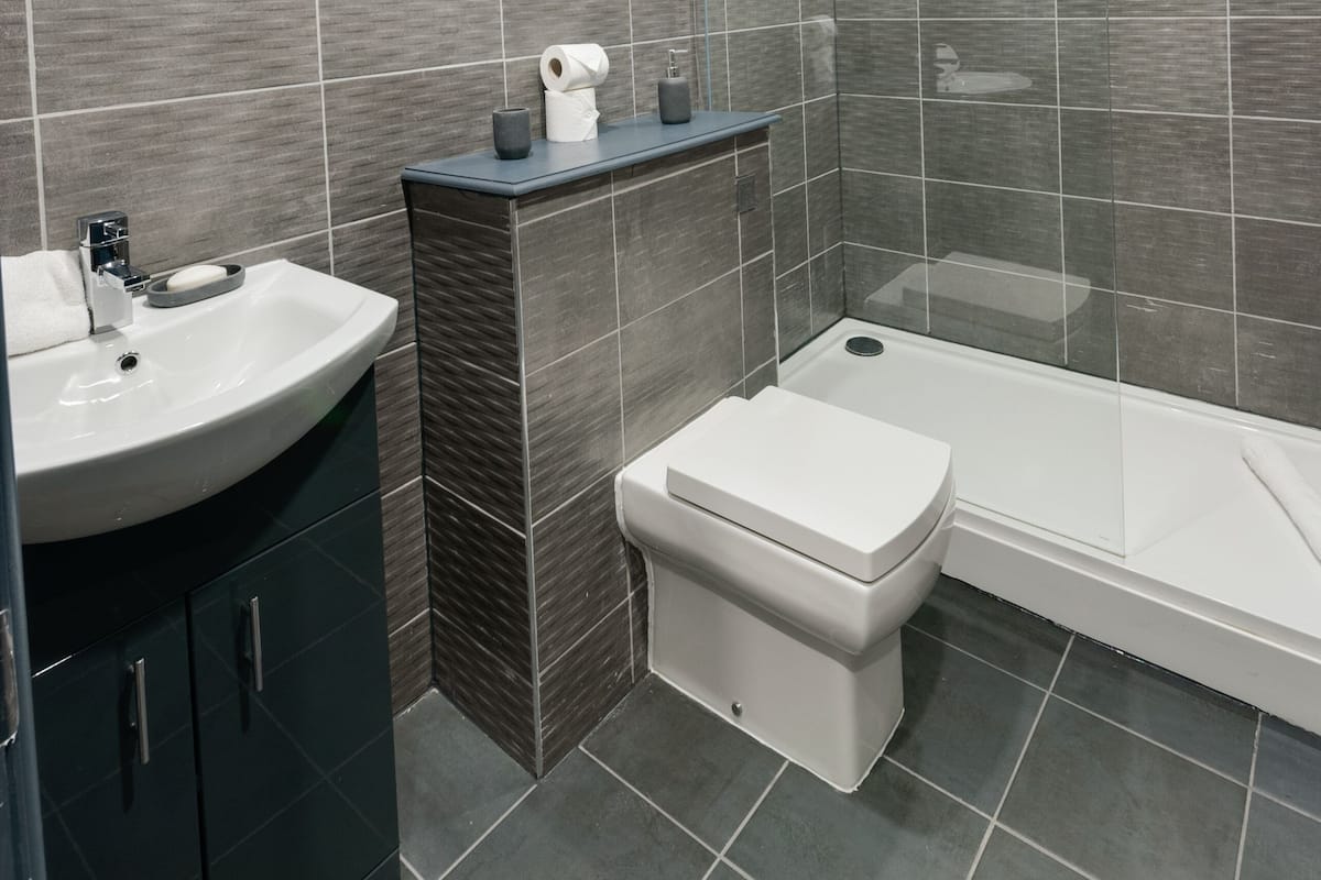 A modern bathroom with a sink, toilet, and shower area.