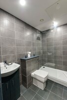 Un baño moderno con lavamanos, inodoro y zona de ducha.