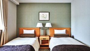 Habitació d'hotel amb dos llits, una tauleta de nit, una làmpada i un quadre al mur.
