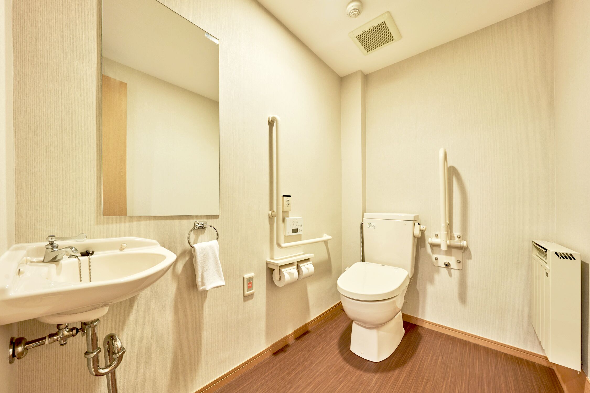 A standard hotel bathroom with a sink, toilet, and mirror.