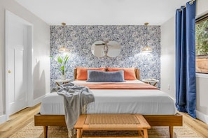 A bedroom with a bed, bedside tables, a mirror, and a window with curtains.