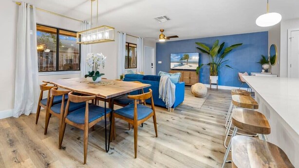 Ein modernes Wohnzimmer mit Essbereich, einer blauen Akzentwand und einem großen Fenster.