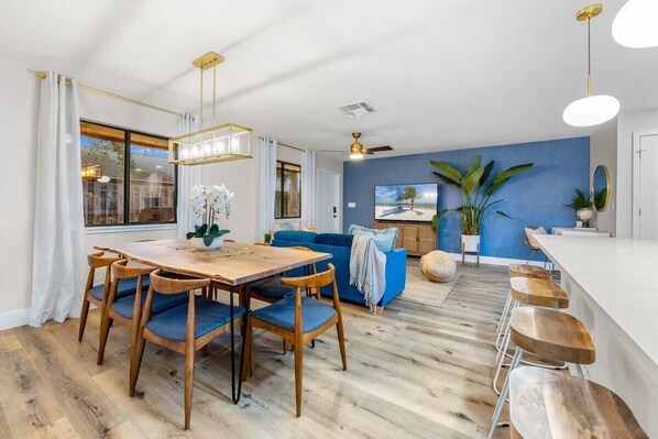 Ein modernes Wohnzimmer mit einem Holzesstisch, einem blauen Sofa und einem großen Fernseher.
