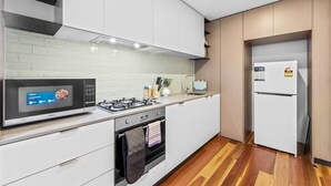 A modern kitchen with white cabinets, a microwave, stove, oven, and a white refrigerator.
