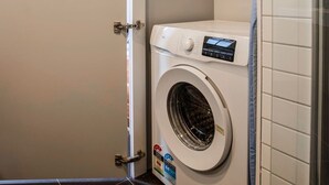 A compact, modern laundry room with a front-loading washing machine and a small drying unit.
