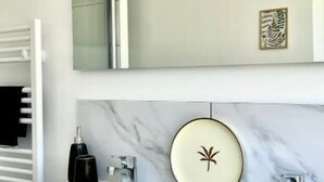 Une salle de bain moderne avec deux lavabos, un grand miroir et un porte-serviettes.