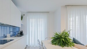Eine moderne Küche mit weißen Schränken, einer schwarzen Arbeitsplatte und einem Essbereich mit weißem Tisch und Stühlen.