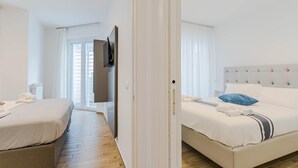 Ein Hotelzimmer mit einem Bett, einem an der Wand befestigten Fernseher und einem Fenster mit Vorhängen.