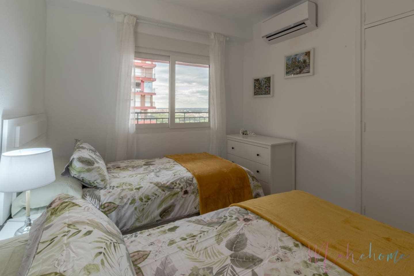 Ein Schlafzimmer mit zwei Betten, einem Fenster, einem Nachttisch, einer Lampe und einer Kommode.
