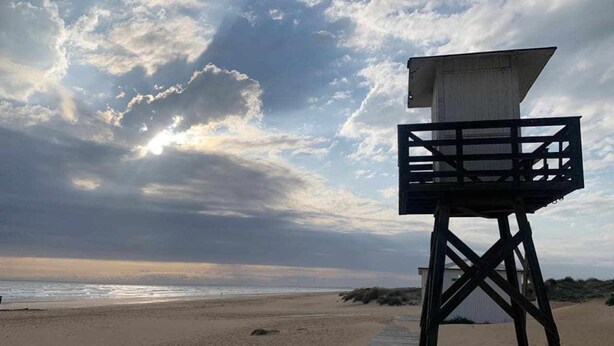 A lifeguard tower on a beach with a clear sky and ocean in the background.