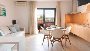 A modern apartment with a dining area, kitchenette, and a balcony with a view.