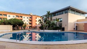 A swimming pool surrounded by modern buildings, with a clear sky above.