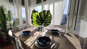 A dining table set with blue plates, silverware, and a large green plant in a vase. - En la Misma Playa Nuevo 3 Dormit , Vistas al mar (Punta Umbria)