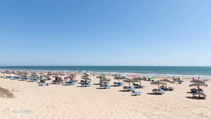 A beach with rows of sun loungers and umbrellas, a clear sky, and the ocean in the background. - En la Misma Playa Nuevo 3 Dormit , Vistas al mar (Punta Umbria)
