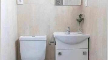 A small, compact bathroom with a toilet, sink, and mirror.