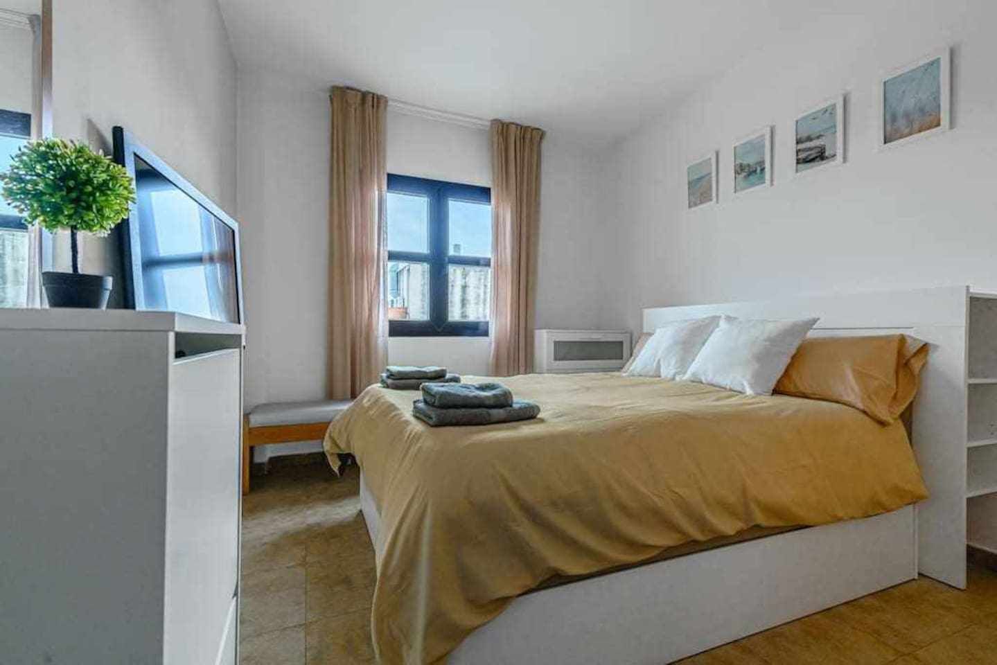 Een slaapkamer met een bed, een bureau, een stoel, een raam en een kleine plant.