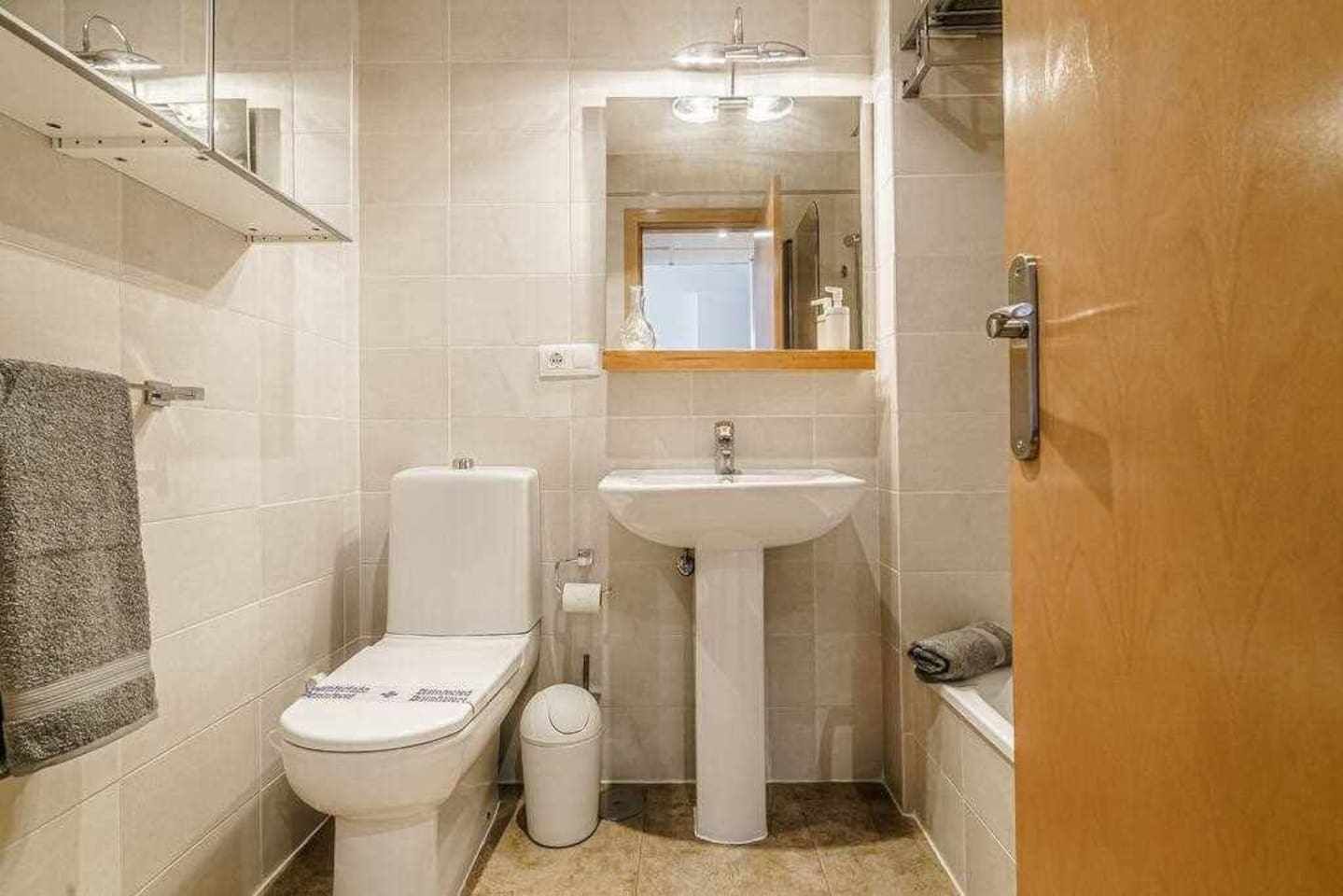 A small bathroom with a toilet, sink, and shower.