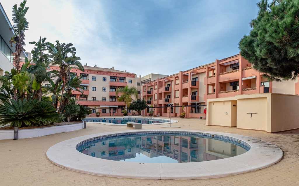 Un patio con una piscina central, rodeado por edificios de varios pisos con balcones.